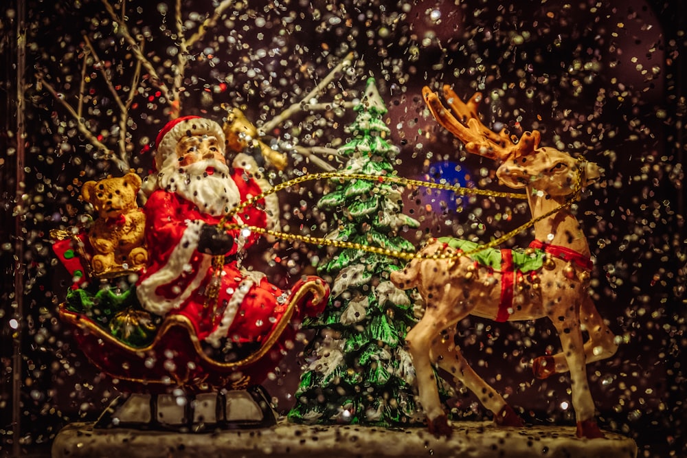 Santa Claus riding sleigh holding rope of reindeer figurine