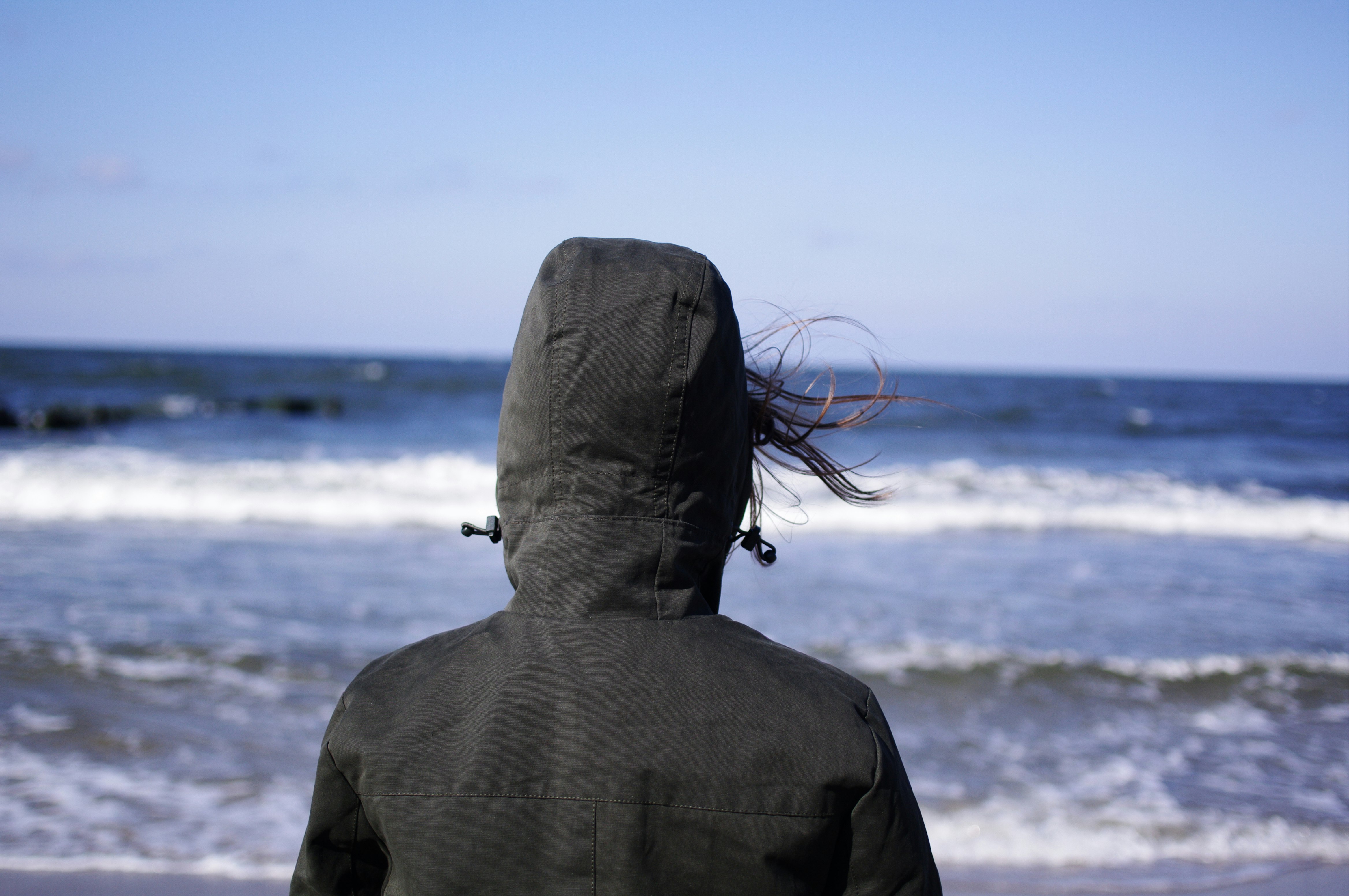 person wearing hoodie facing sea