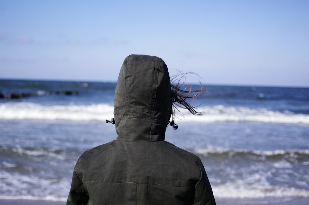 person wearing hoodie facing sea, Chilly and super windy