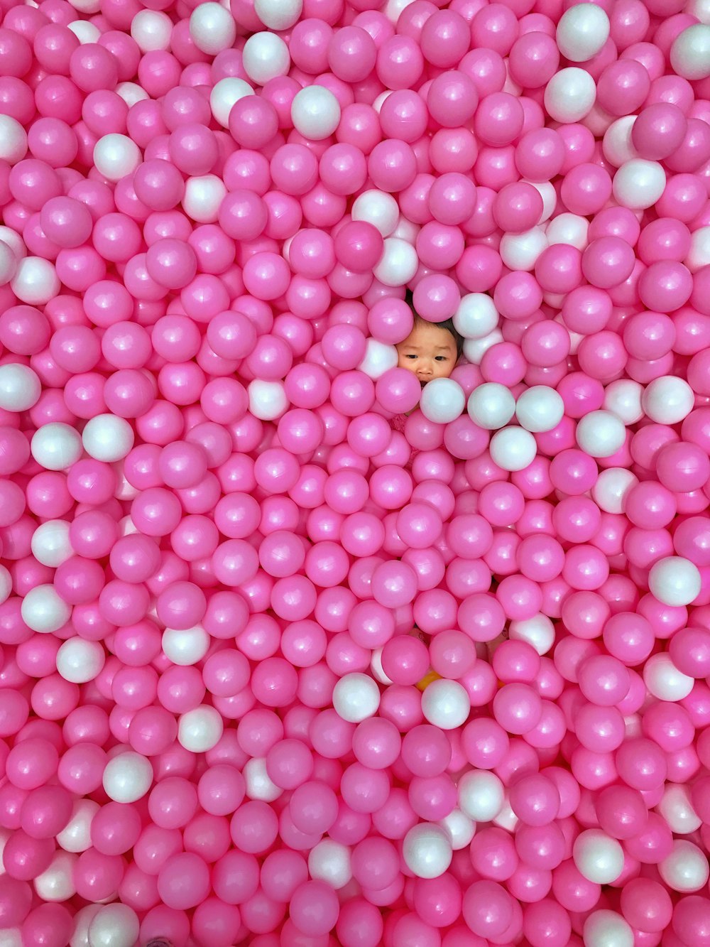 toddler on pink and white ballpit