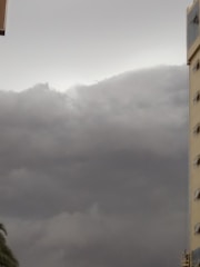 Dark gray storm clouds cover the sky, while a tall building with several windows is visible on the right side. The atmosphere appears overcast, suggesting an impending storm.