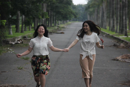A joyful couple walking hand in hand through a sunlit park.