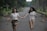A joyful couple walking hand in hand through a sunlit park.