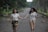 A joyful couple walking hand in hand through a sunlit park.