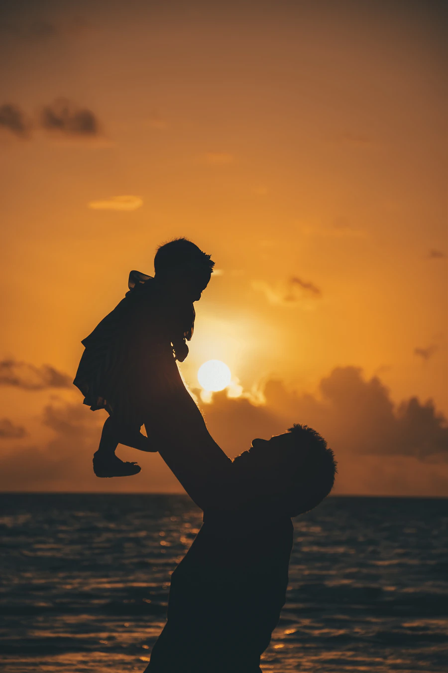 Papá cargando a su bebé en brazos al atardecer