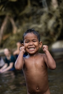 A cheerful toddler splashing gently in a shallow pool with a friendly instructor nearby.