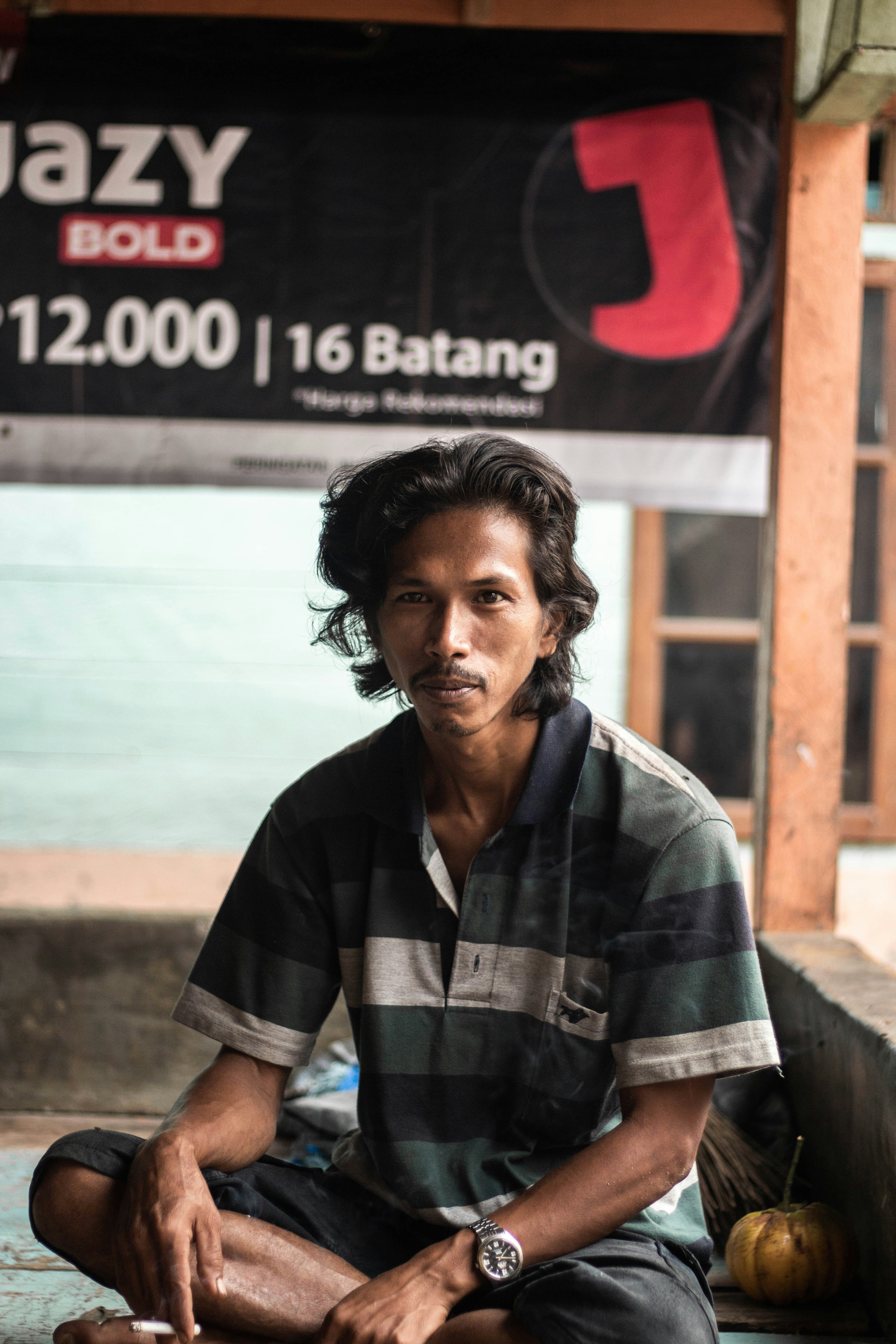Pria mengenakan kaos polo duduk di permukaan