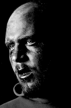A black-and-white portrait with intense contrast and a minimalist background.