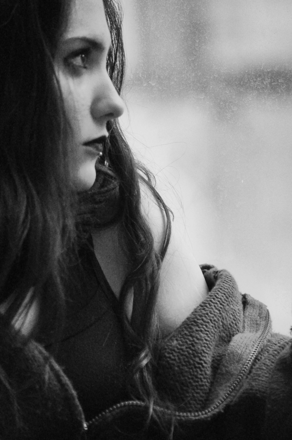 grayscale photography of woman looking upward near window