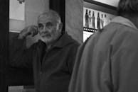 A candid shot of a man in a worn jacket leaning against the bar counter, lost in thought.