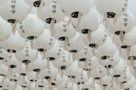 A serene installation of hanging paper lanterns casting soft light in a dark room.