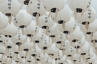 A serene installation of hanging paper lanterns casting soft light in a dark room.