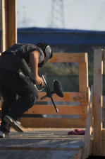 A dynamic urban paintball player taking cover behind industrial structures.