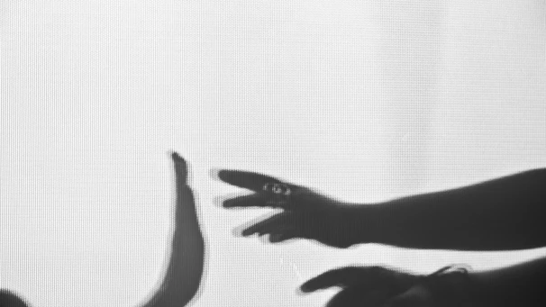 Monochrome image of two hands shaking over a sleek architectural blueprint