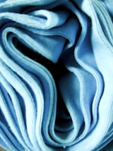 Close-up of premium textile fabric rolls in blue and green tones.