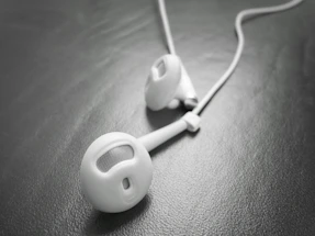 Close-up of sleek titanium in-ear monitor resting on a dark textured surface with warm gold accents.
