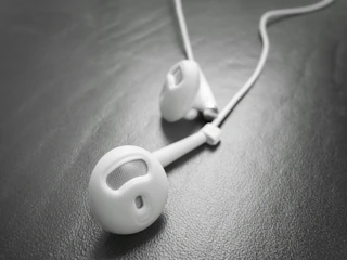 Close-up of sleek silver headphones resting on a black glass surface with subtle gold reflections