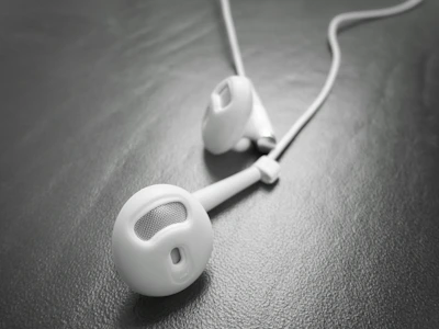 Close-up of a sleek Luxear earbud resting on a polished marble surface.
