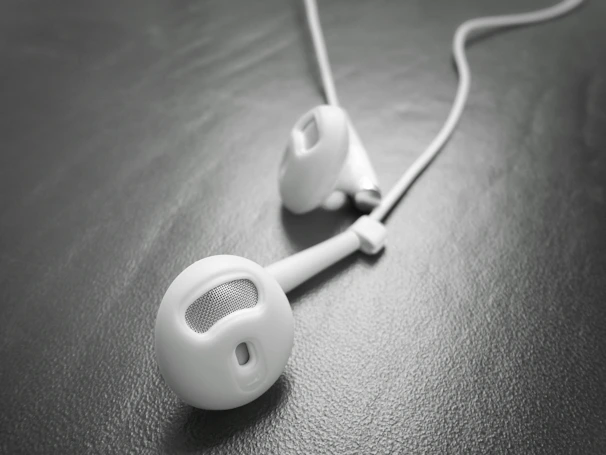 Close-up of a pair of stylish black earbuds with a subtle reflection on a white background.