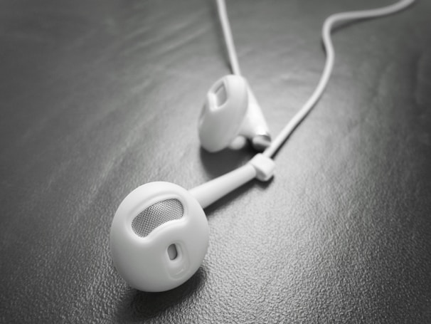 A close-up shot of sleek, modern earbuds resting on a wooden surface.