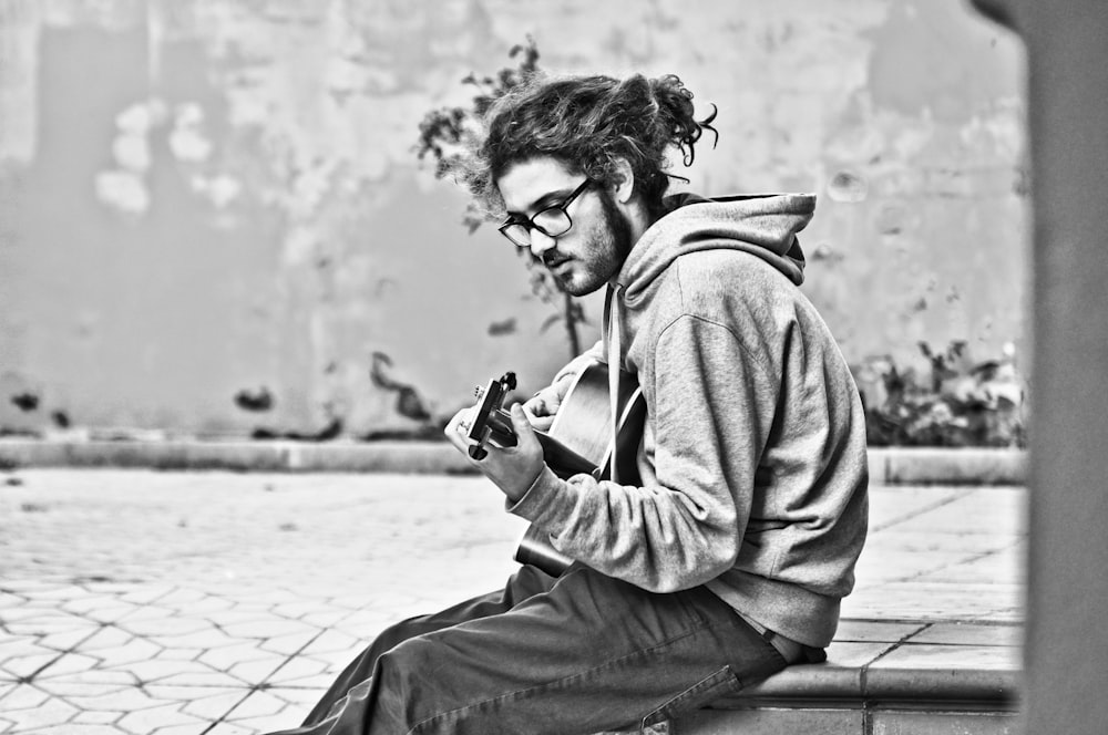 man playing guitar grayscale photo