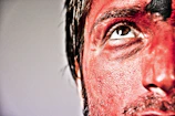 Close-up of an actor's face painted with theatrical makeup under stage lights.