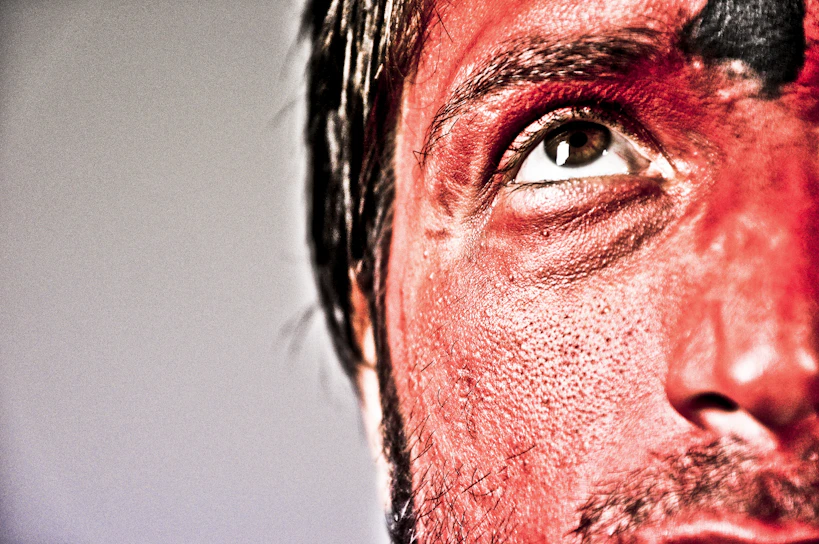 A vibrant close-up of a character designer applying intricate SFX makeup under dramatic lighting.