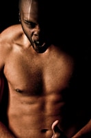 Close-up of a muscular athlete mid-workout under red lighting and dark shadows