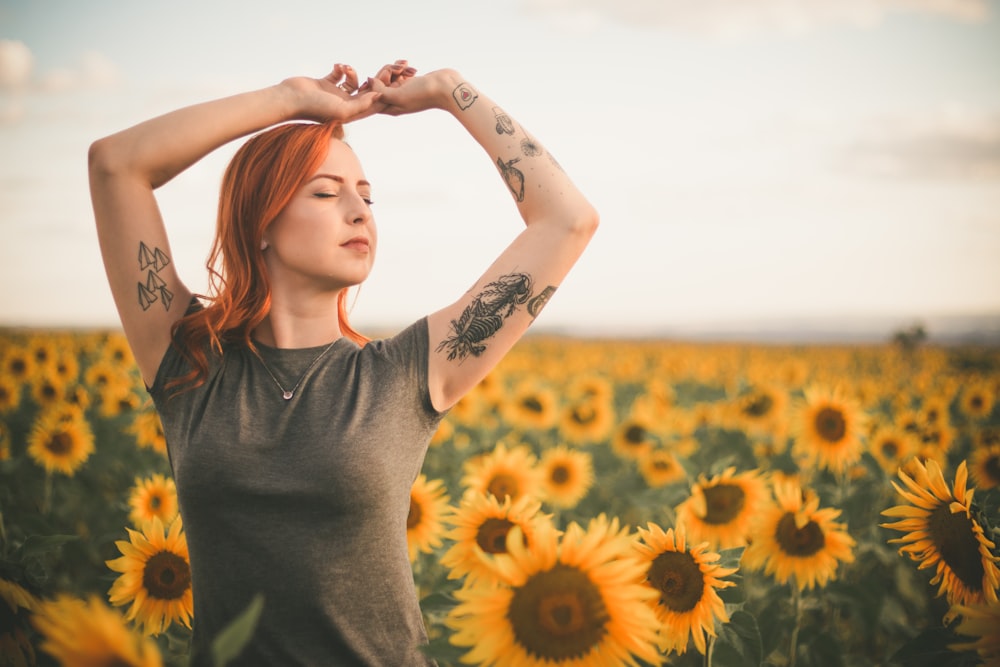 woman wearing gray crew-neck shirt on sunflower fields