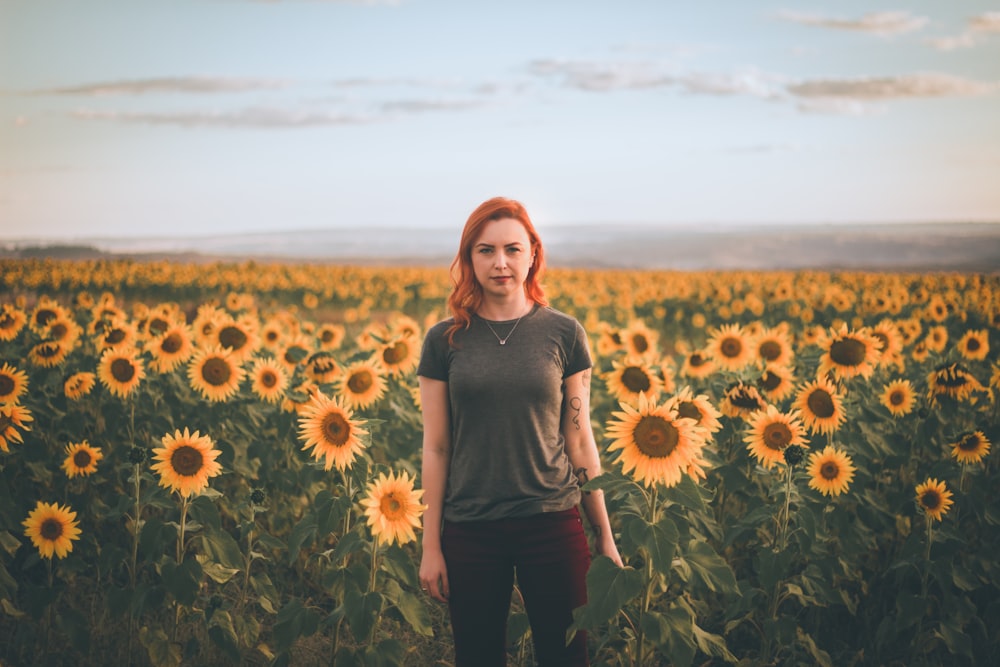 woman standing at bed of sunflowers