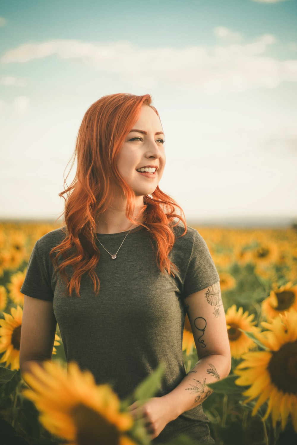 woman wearing gray t-shirt surrounded sunflowers