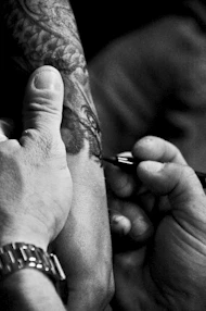 Close-up of a tattoo artist working on a detailed arm tattoo.