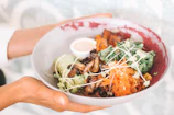 Close-up of hands holding a bowl of fresh, colorful food, representing nourishment without restriction.
