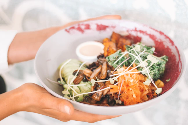 Close-up of hands holding a bowl of fresh, colorful food, representing nourishment without restriction.