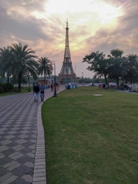A scenic view of the Eiffel Tower at sunset with people enjoying the park.