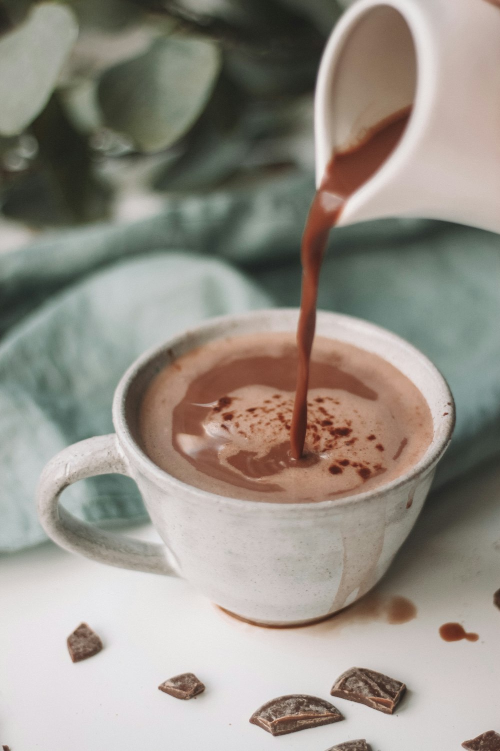 Chocolade melk die wordt gegoten in een wit koffiekopje