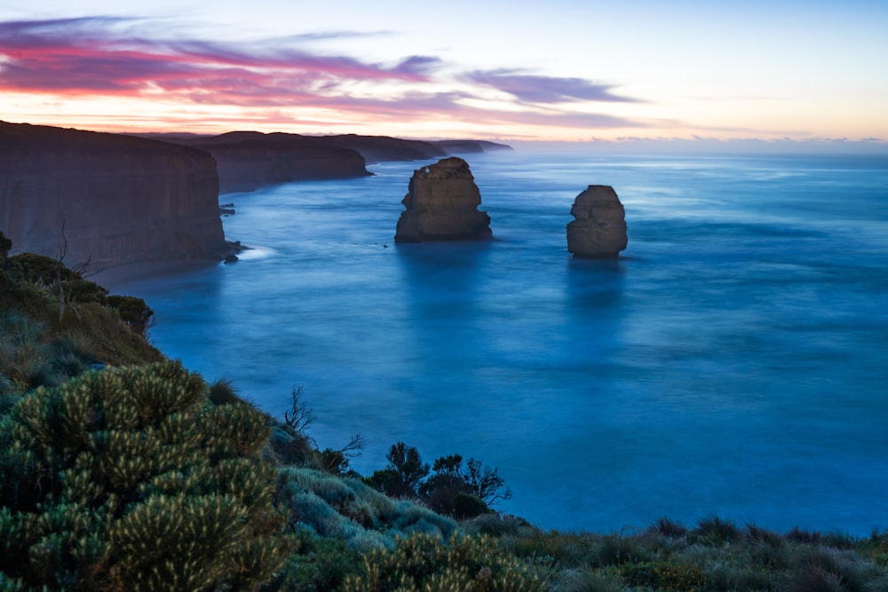 two brown rock formation on body of water