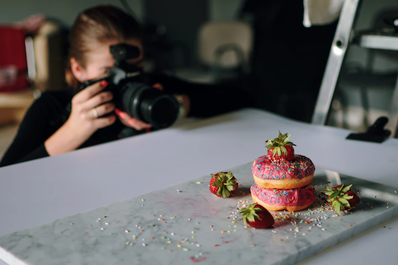 Fotógrafa fotografando donuts sobre a mesa