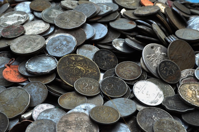 A collection of assorted old coins spread out on a wooden table.