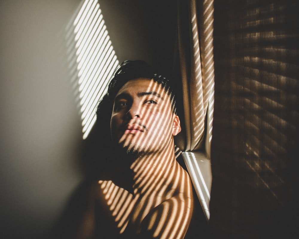 man leaning beside window