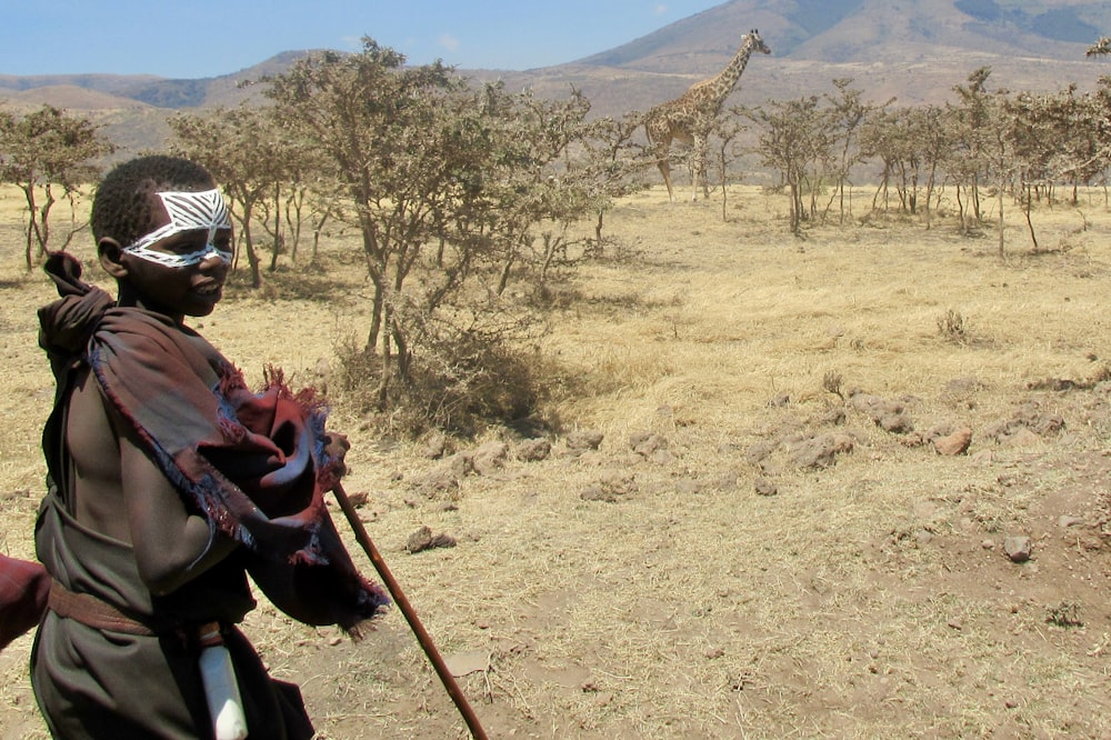 boy standing while holding brown stick