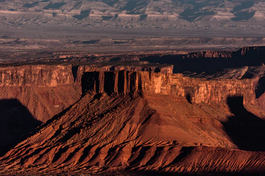 A striking view of Elephant Rock at sunset, with warm golden light casting long shadows over the desert landscape.