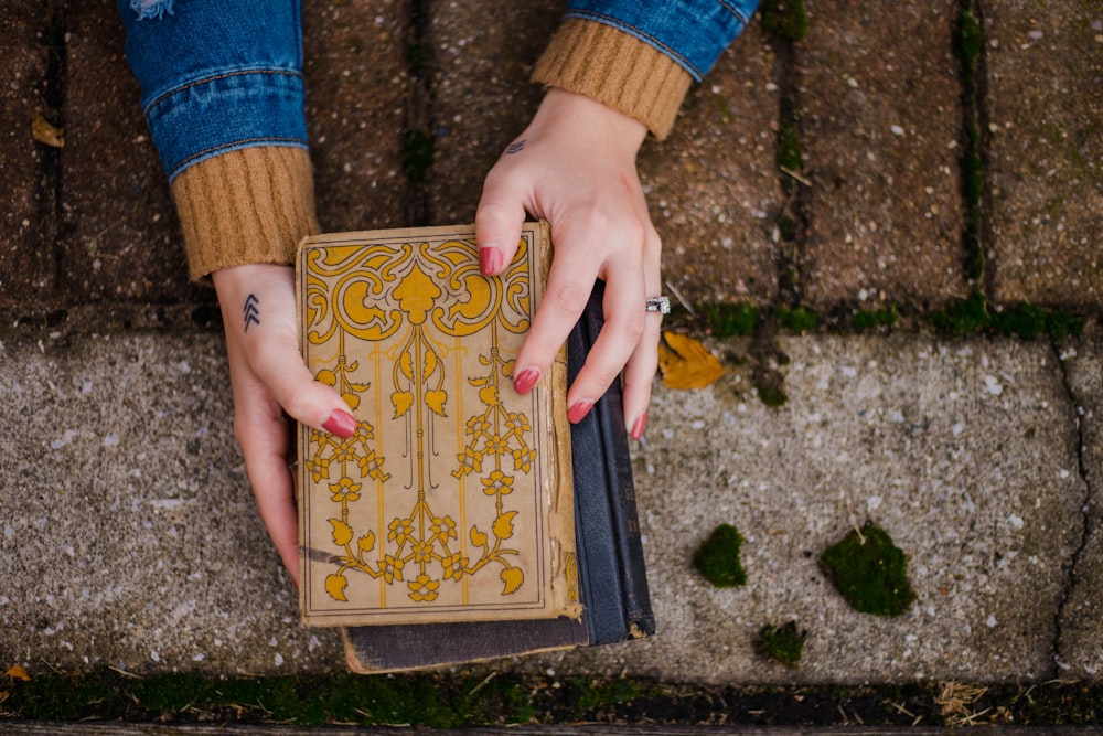 person holding beige and black books