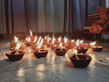 A collection of spiritual books stacked neatly with a glowing diya lamp on top.