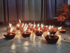 Close-up of sacred diya lamps glowing softly beside ancient astrology texts