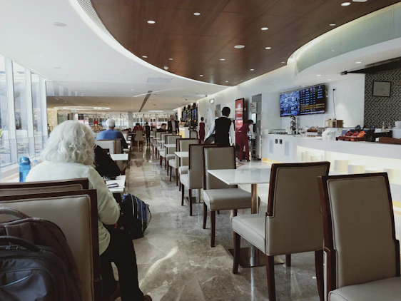 A serene airport lounge with plush seating, soft lighting, and travelers relaxing peacefully.