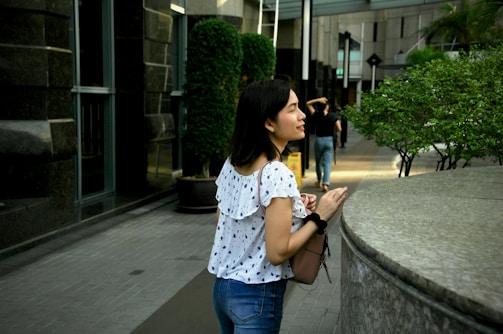 Woman carrying a chic handbag while smiling outdoors.