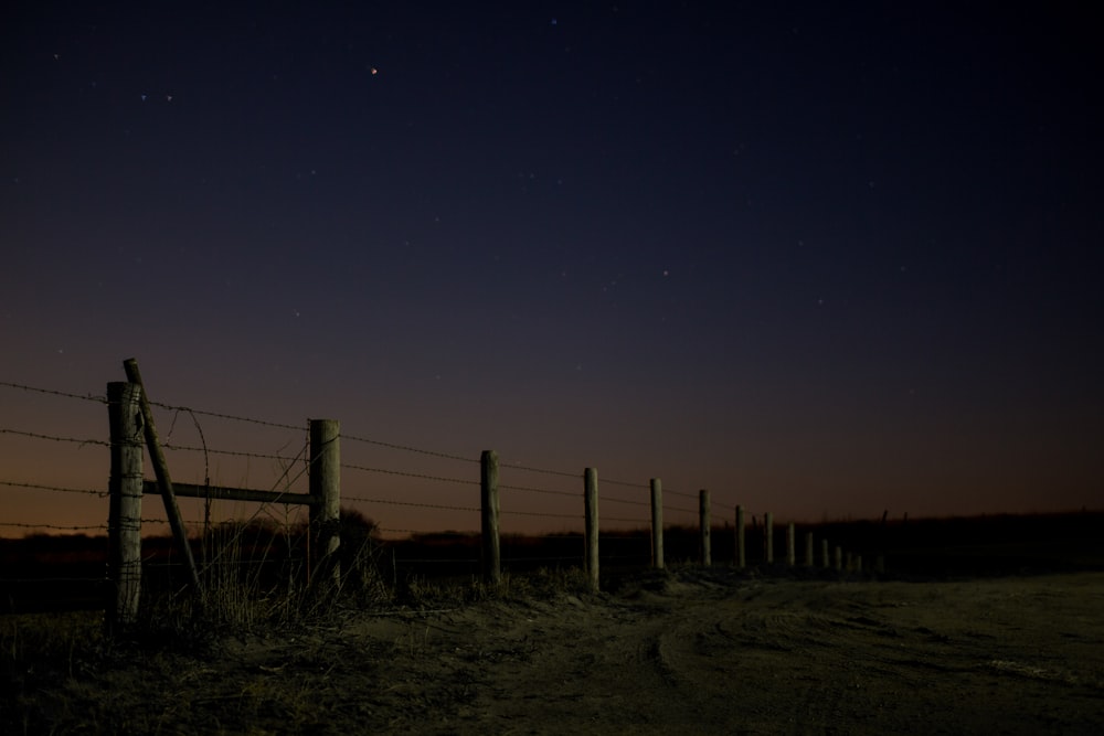 photo de paysage de poteau et de clôture en fil de fer pendant la nuit