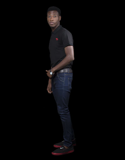 Close-up of a man wearing a sleek black Percy polo with subtle embroidered logo, standing against a minimalist gray background.