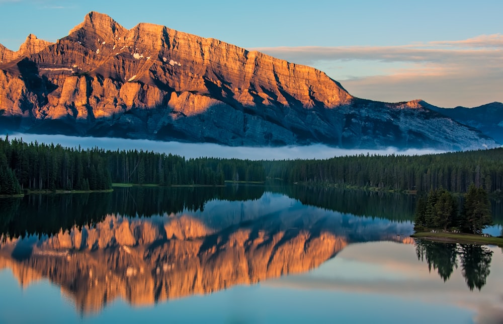 brown rock mountain with the distance of green trees near body of water